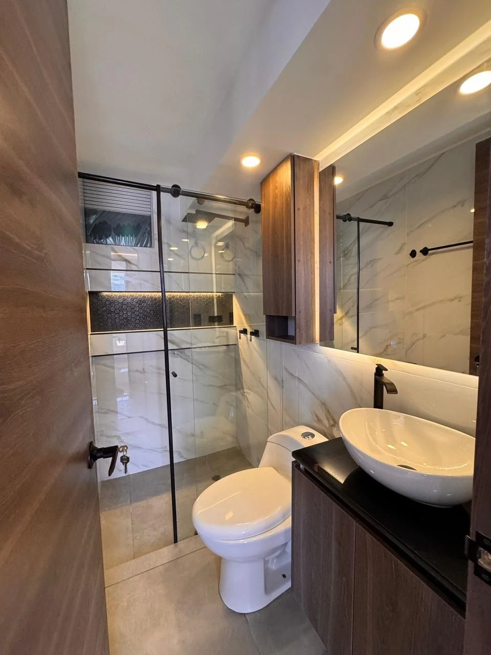Baño con ducha, nicho hexagonal LED y mueble oscuro