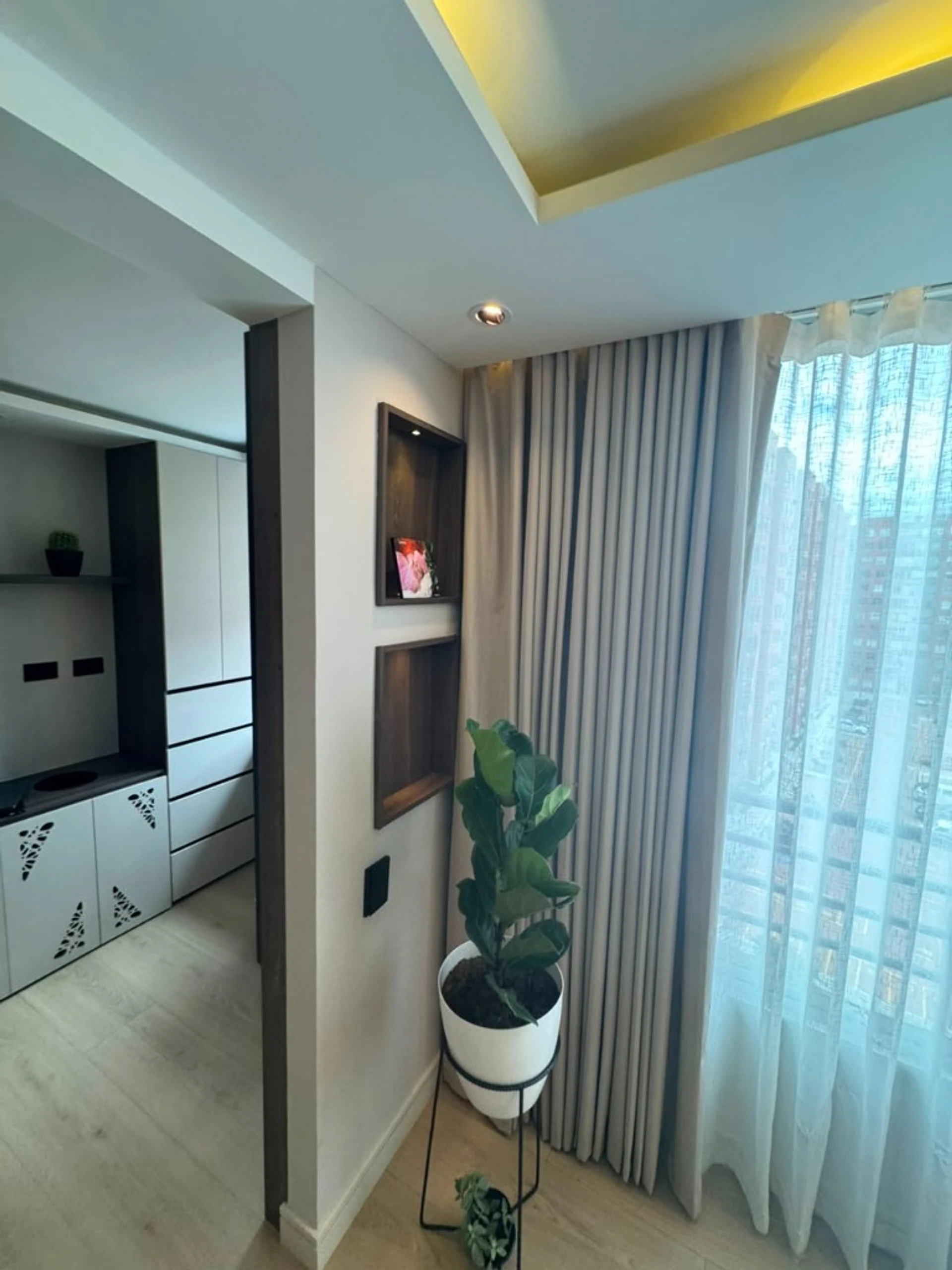 Pasillo con nichos de madera, cortinas y cenefa LED hacia la cocina