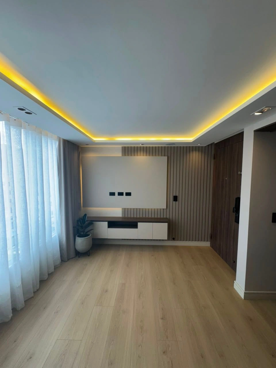 Sala con cenefa LED, panel de TV y piso en roble, remodelación en Bogotá